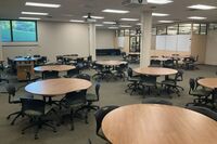 View of room showing student group table seating and exit door at right rear of room