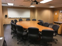 Photo of back of room from front of room with a half moon conference table.