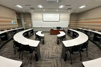 Front of room view with lectern center in front of markerboard, screen partially lowered