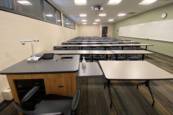 Back of room view of student table and chair seating and exit doors at right rear of room