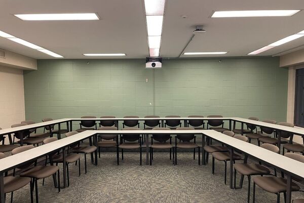 Back of room view of student tiered fixed tables and chairs seating 
