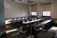 Back of room view of student table and chair seating and markerboard on back wall