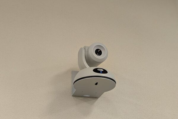 Camera mounted to a wall and instructor enabled adjustments to the lens to allow the instructor to be "seen" by the camera in more locations around the room