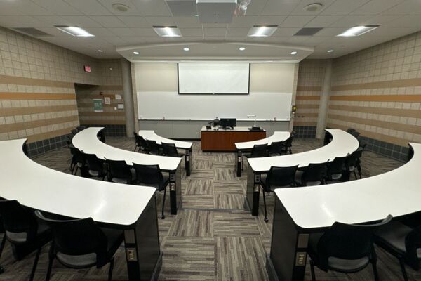 Front of room view with lectern center in front of markerboard, screen slightly lowered