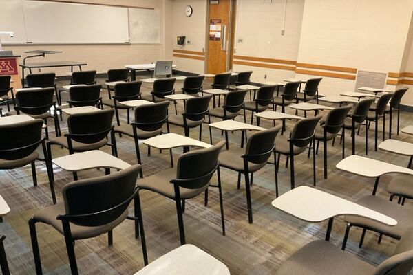 Front of room view with lectern on left in front of markerboard, exit door on right wall of room