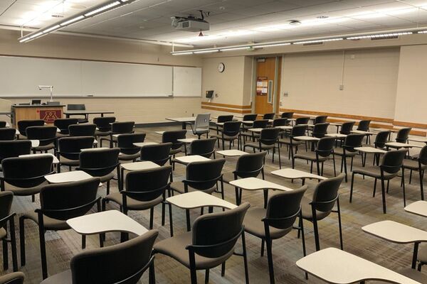 Front of room view with lectern on left in front of markerboard, and exit door on right wall