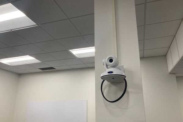 Camera mounted to a pillar and instructor enabled adjustments to the lens to allow the instructor to be "seen" by the camera in more locations around the room