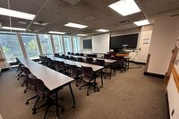 Front of room view with lectern on right in front of chalkboard and projection screen partially raised