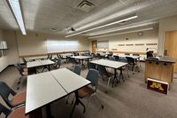 Back of room view of student table and chair seating and markerboard on rear wall