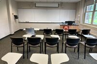 Front of room view with lectern on right side and projection screen partially lowered