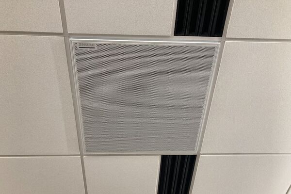 White 2x 2 tile mounted in the ceiling to provide microphone coverage over student seating