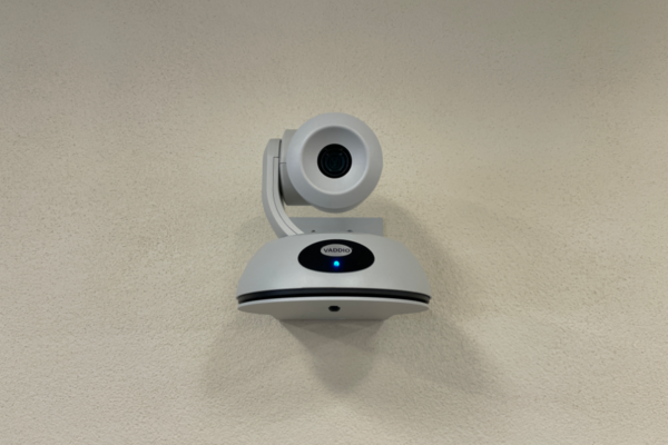 Camera mounted to a wall and instructor enabled adjustments to the lens to allow the instructor to be "seen" by the camera in more locations around the room