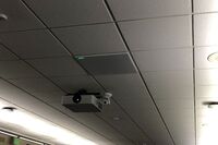 Camera mounted to ceiling and instructor enabled adjustments to the lens to allow the instructor to be "seen" by the camera in more locations around the room and 2’ x 2’ tile mounted in the ceiling to provide microphone coverage over student seating 