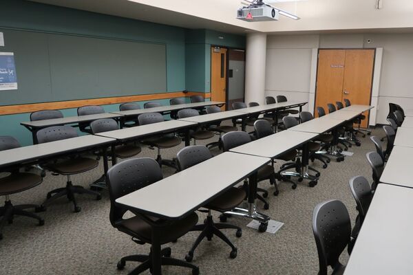 Back of room view of student table and chair seating and  exit door at rear right of room