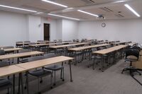 Rear of room view of student table and chair seating on casters and exit door on right side of room