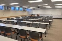 Back of room view of student table and chair seating and exit door at left rear of room