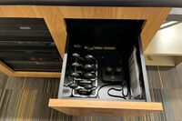 Pedestal - inside view of drawer showing two wireless mics in charging base and assistive listening devices in charger
