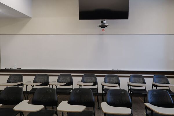Back of room view of student tablet arm seating, confidence monitor, camera, and markerboard at rear of room