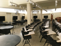 Photo of back of room from front of room with group work tables along back wall.