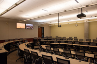 View from audience right side perspective looking towards rear of classroom showing rear exit door, instructor camera, rear self view monitors, and audience seating