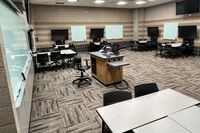 Back of room view of student collaborative table and chair seating and student displays and markerboards on side walls