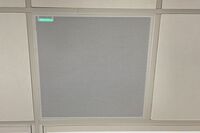 White 2x 2 tile mounted in the ceiling to provide microphone coverage over student seating