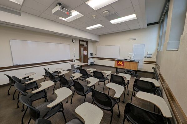 Front of room view with lectern on right in front of markerboard and  exit door on front left wall