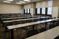 Back of room view of student tables and chairs and markerboard on rear wall