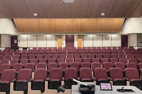 Back of room view of student auditorium seating and exit door at right and left rear of room