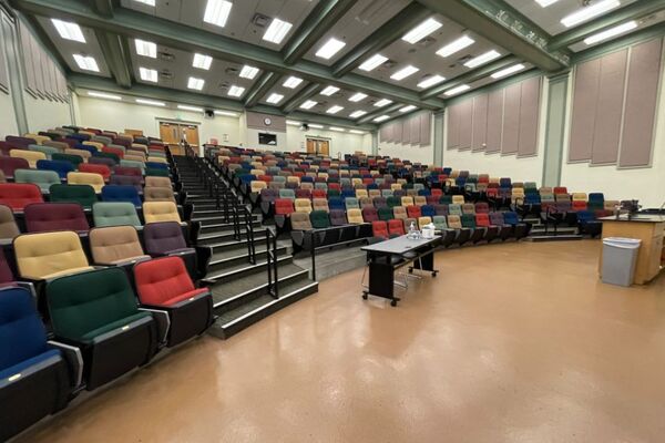 Back of room view of student auditorium seating and control room booth and double exit doors on left