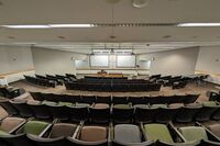 Front of room view with lectern center in front of markerboard and exit to right front 
