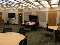 Photo of back of room from front of room with group work tables.