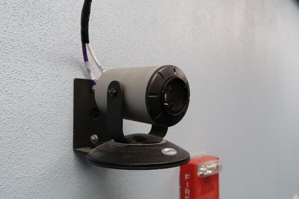 Camera mounted to a wall and instructor enabled adjustments to the lens to allow the instructor to be "seen" by the camera in more locations around the room