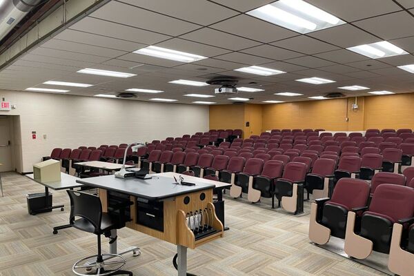 Back of room view of student auditorium seating and exit door at front left