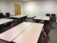 Photo of back of room from front of room with tables set for 4 person seating.
